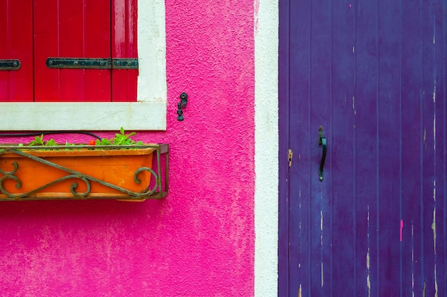 Pink painted facade with window and violet wooden door Burano island Italy