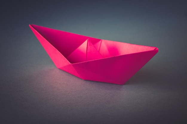 Pink paper boat origami isolated on a grey background