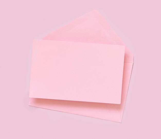 Pink paper card and envelope on pink top view. Minimal scene with blank card mockup. Educational and girly concept,  space for text.