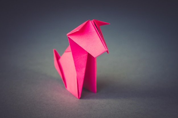 Pink paper dog origami isolated on a grey background