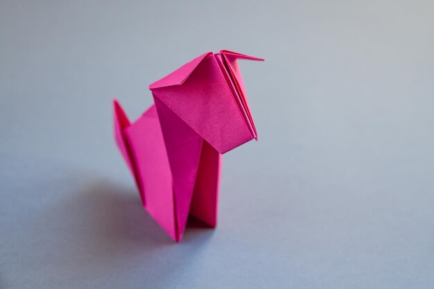 Pink paper dog origami isolated on a grey background