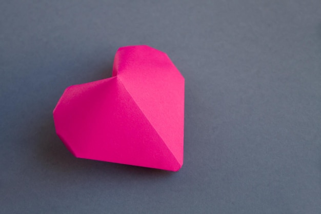 Pink paper heart origami isolated on a grey background