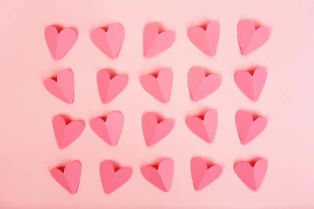 Pink paper hearts arranged in rows on pink background