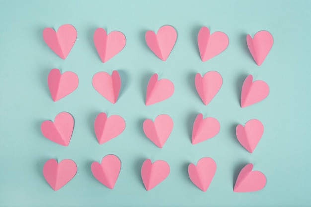 Pink paper hearts on mint background. Flat lay.