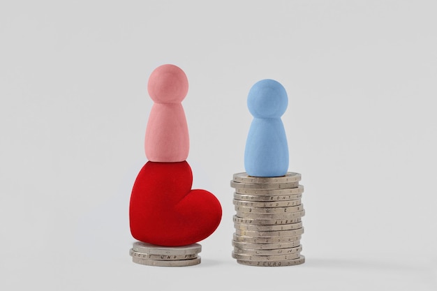 Photo pink pawns with heart and blue pawn on piles of coins - concept of woman power and gender pay gap