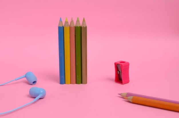 Pink pencil sharpener with several kinds of colored pencils on a pink background