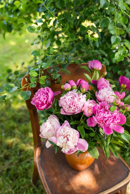 Pink peony in a jug on an old vintage wooden chair rustic still life A bouquet for a wedding or birthday