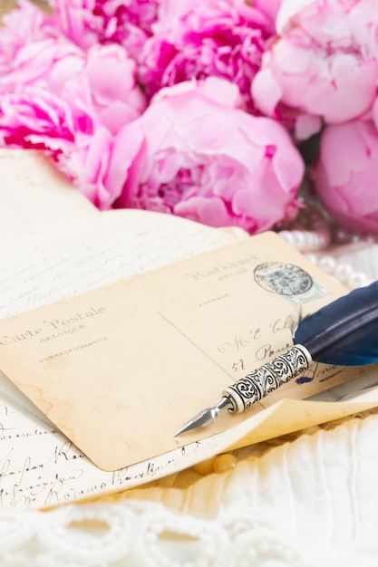 Pink peony with antique letter with copy space and feather pen on white lace