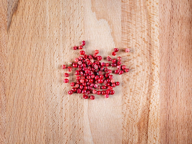 Photo pink pepper on a wooden surface. close up. brazilian pepper. holy florida