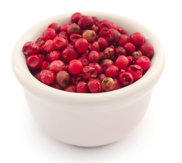 Pink peppercorn in ceramic bowl over white background