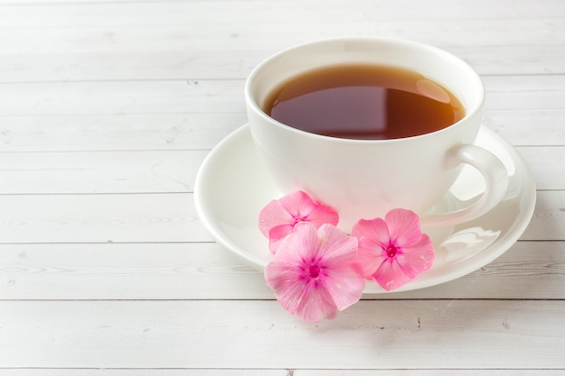 Pink Phlox flowers and a Cup of coffee on a white table. 