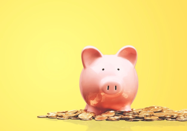 Pink piggy bank and coins on background