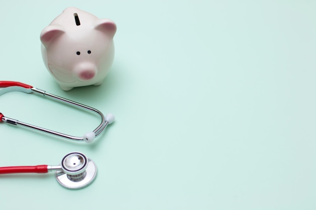 Photo pink piggy bank with stethoscope on green background