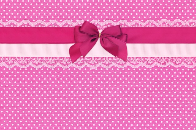 Pink polka dot textile background with ribbons and bow