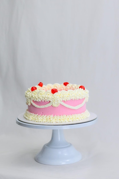 Pink red cupcake for birthday celebration isolated on white smoothing topper with spatula wearing gloves in professional kitchen