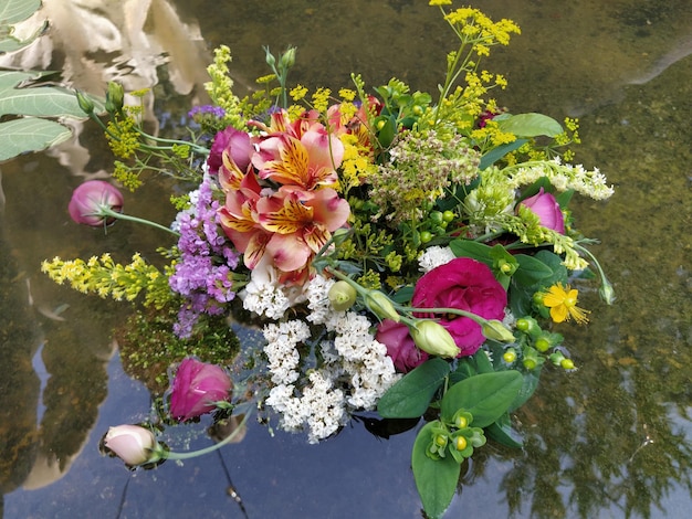 Pink and red roses in a bouquet floating in the water of a pond Plucked buds as decoration for a summer holiday Ivan Kupala summer solstice Harvest festival