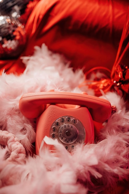 Pink retro phone on bed with red silk gloss sheets on valentines day