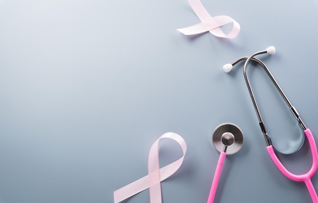 Pink ribbon and stethoscope on pastel paper background for supporting breast cancer awareness month campaign