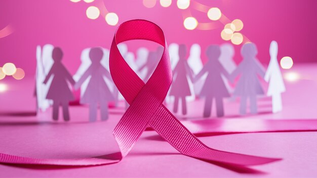 Photo pink ribbon a symbol of breast cancer awareness standing prominently in the center of a group of paper cutouts of women holding hands generative ai