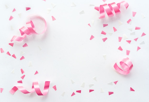 pink rolling ribbon and confetti on white background with copy space for festival carnival design 