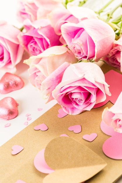 Pink roses and hand crafted gift bag on a white background.