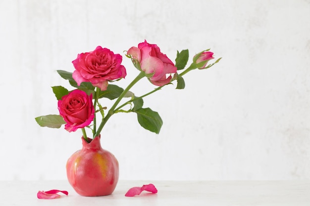 Pink roses in pink vase on background old white wall