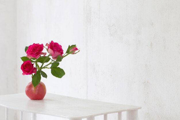 Pink roses in pink vase on background old white wall