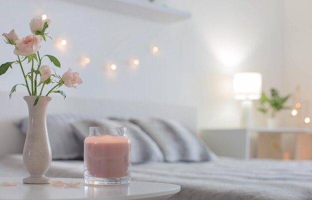 Pink roses in vase on table in bedroom