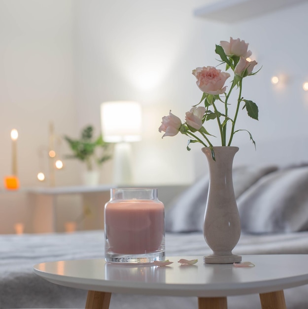 Pink roses in vase on table in bedroom