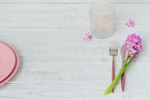 Pink rustic place setting with purple hyacinth flower candles and linen napkin on white wooden background