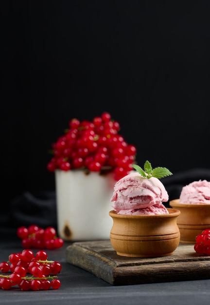 Pink scoops of popsicles with red currants on a black table Ice cream