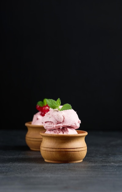 Pink scoops of popsicles with red currants on a black table Ice cream