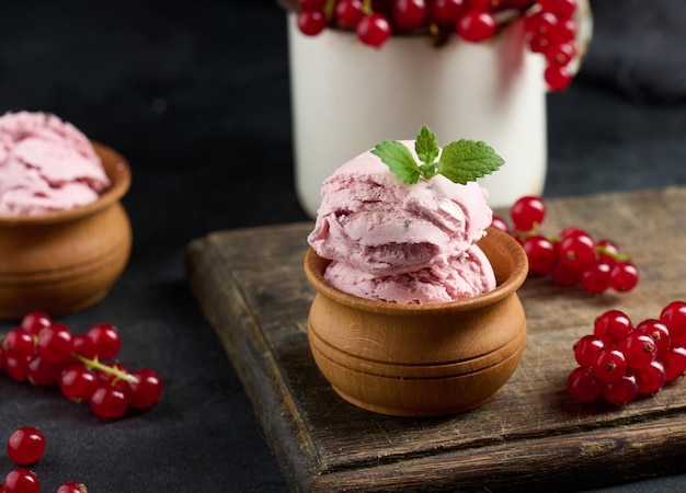 Pink scoops of popsicles with red currants on a black table Ice cream