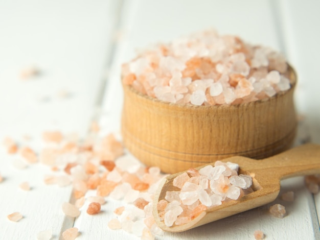 pink sea salt heap of sea salt in a wooden bowl and scoop on a light wooden background closeup