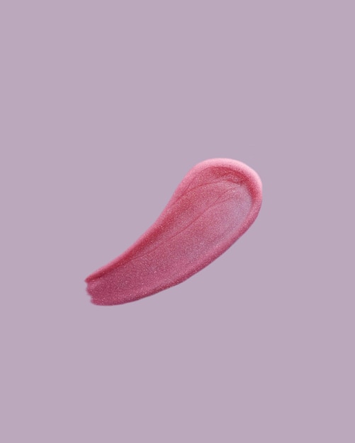 Pink shimmering lip gloss swatch texture on purple background Lipstick smudged cosmetic product