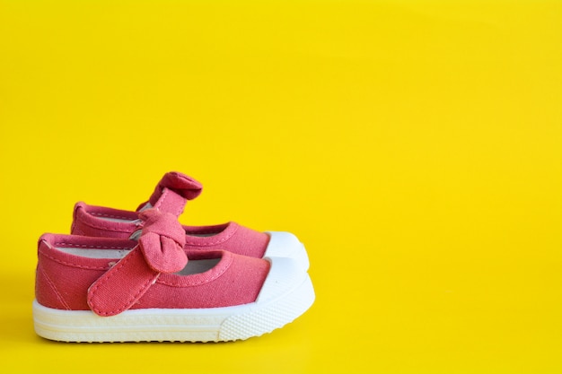 Pink shoes for children on yellow .