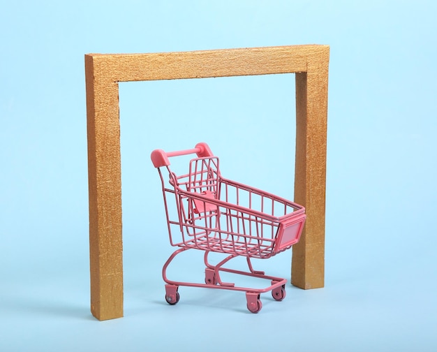 Pink shopping trolley with Golden frame arch on blue background Minimalism still life Concept art