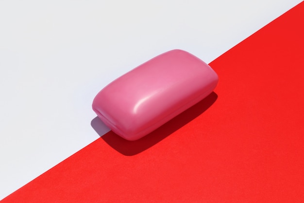 Pink soap bar on white and red background.