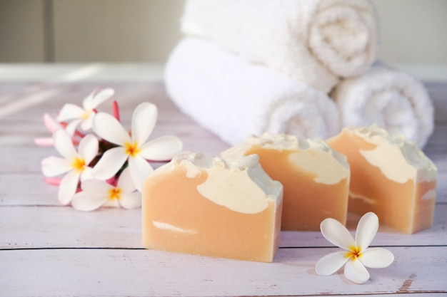 Pink soap is placed on the table, flowers and towels are placed on its side.