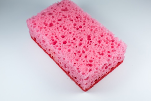 Pink sponge for washing dishes on white background. Artificial fiber not eco-friendly tool. Things for kitchen.