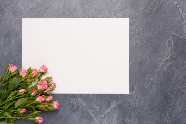 Pink spray roses and blanl list on grey background. Top view. Copy space. Birthday Woman's Day Mother's concept. 