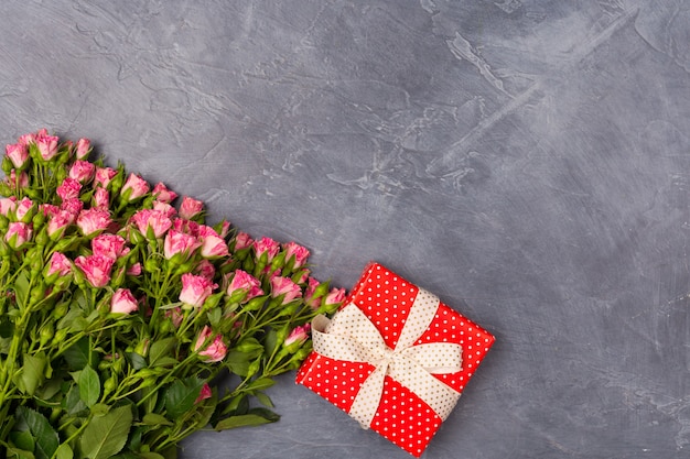 Pink spray roses, gift in red box on grey background. Woman's Day Mother's St. Valentine's Day concept Copy space