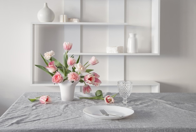 pink spring flowers in white ceramic vase in modern home interior