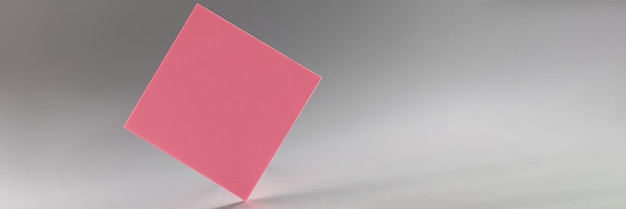 Pink square sticker standing on sharp edge on grey background