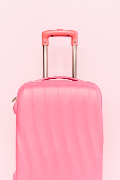 Pink suitcase for travelling against pink background