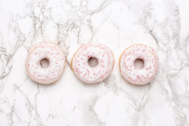 Pink sweet doughnuts on a marble background view from above