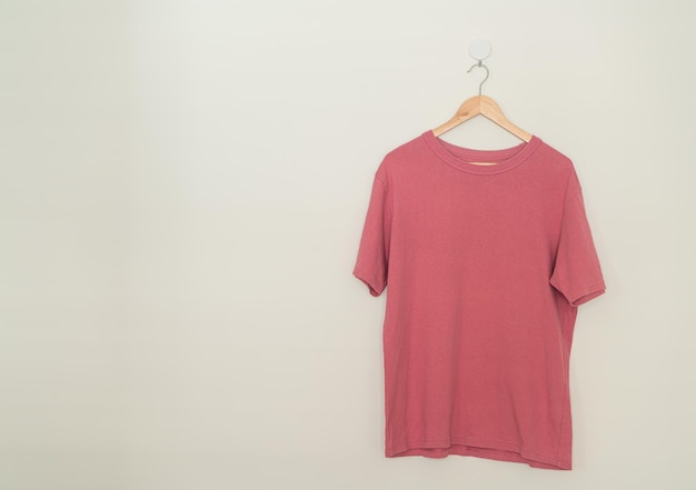 pink t-shirt hanging with wood hanger on wall