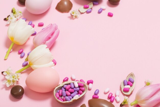 Pink table with chocolate eggs and flowers