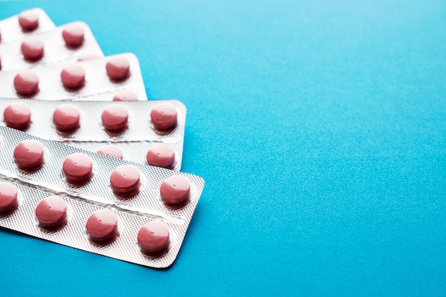 Pink tablets in blisters on a blue background.