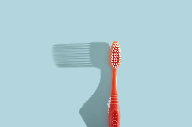 Pink toothbrush on blue background with hard shadow dental care concept